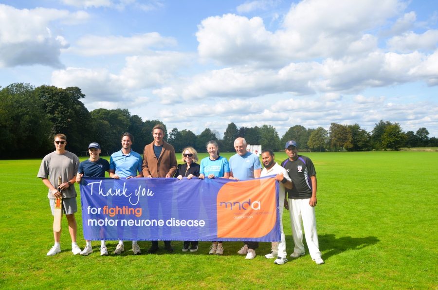 A group of people holding a sign in celebration for the fundraising of the Motor Neurone Disease charity