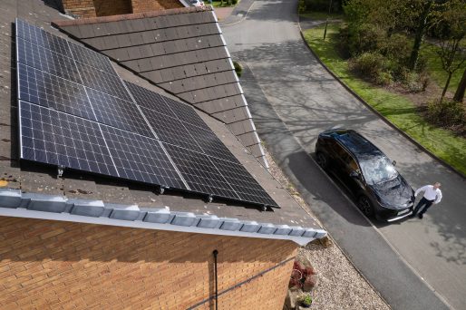 Toyota bZ4X owner in front of a house with solar panels.